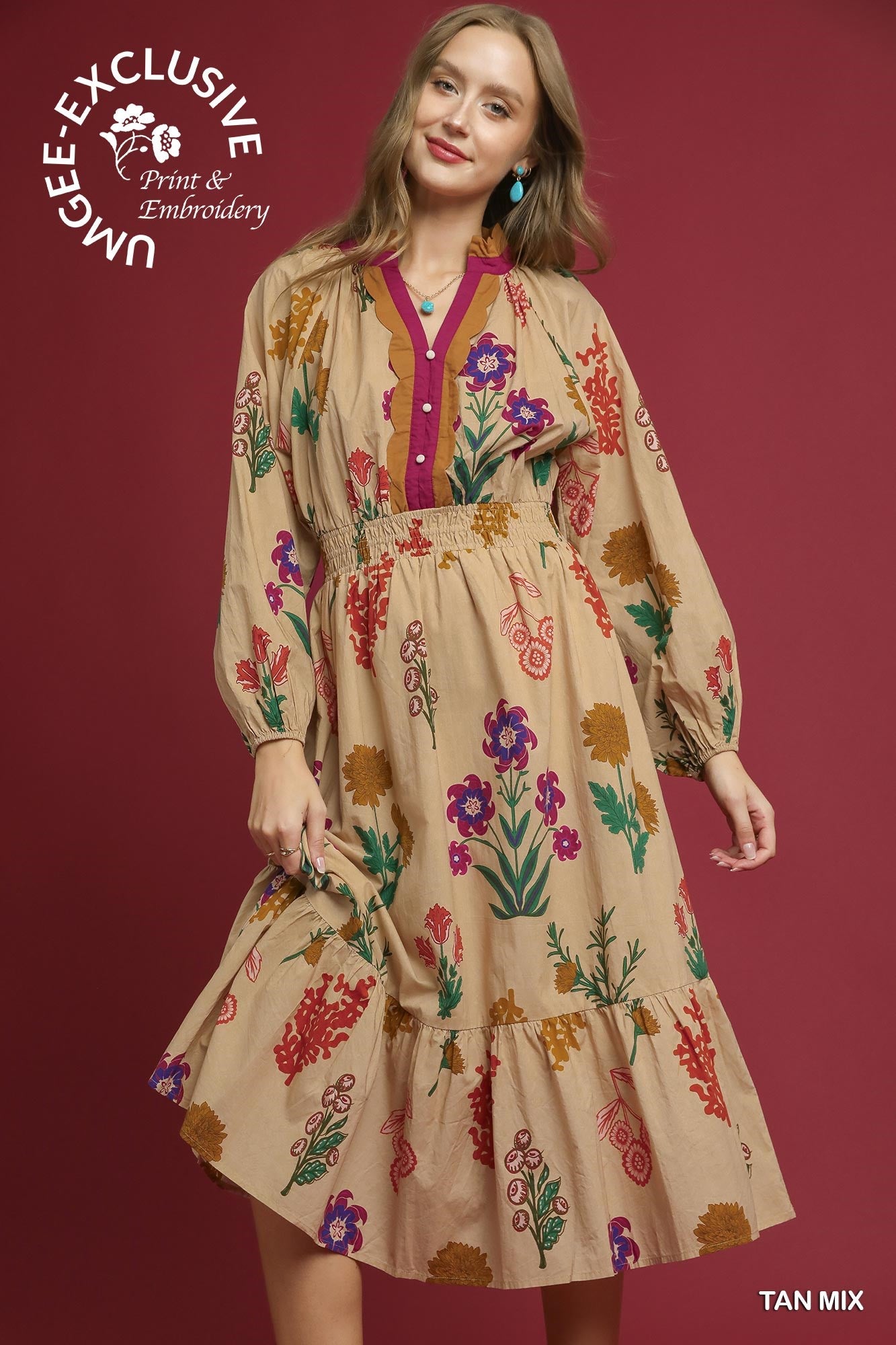 Woman wearing a tan dress with colorful floral embroidery on a red background, featuring Umgee Exclusive branding.