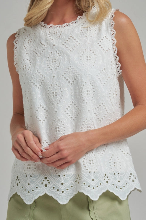 Woman wearing a white sleeveless top with lace details on a gray background